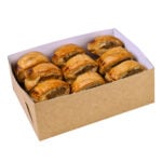 Extra small kraft platter base, with kraft exterior and white interior, filled with nine golden puff pastry sausage rolls, neatly arranged in two rows.