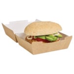 Large kraft clamshell, filled with sesame seed burger with avocado, tomato, patty, and mayonnaise.